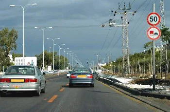 צילום מתוך רכב בדרך רחבה: מכוניות נוסעות לפנינו בשני נתיבים, קו צהוב מפריד במרכז, ומימין ניצבים תמרור עגול עם המספר 50 ותמרור נוסף.